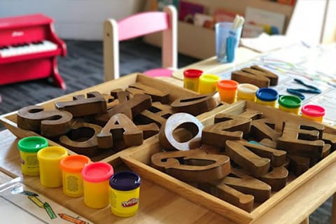 Typischer Raum in einem Kindergarten - Bunte Knete und Bastelmaterial auf einem Kindertisch 